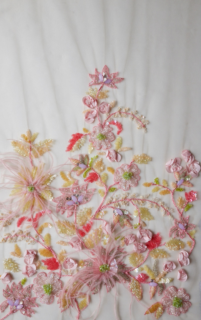 May include: Pink, yellow, and green beaded floral embroidery on a white sheer fabric. The embroidery features delicate flowers, leaves, and feathers.