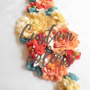 Puede incluir: Primer plano de una colecci&oacute;n de flores de tela hechas a mano en tonos naranja, amarillo y verde azulado. Las flores est&aacute;n dispuestas en cascada y tienen un aspecto delicado y texturizado. El texto "Custom Colors" est&aacute; superpuesto en la imagen. El texto "We make custom colours for a minimum order of 3 pieces" est&aacute; en la parte inferior de la imagen.