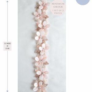 May include: A delicate pink floral trim with pearl accents, measuring 12.6 inches (32 cm) long and 2 inches (5 cm) wide. The trim is perfect for adding a touch of elegance to any project. Minimum order is 1 set of 2 pieces.