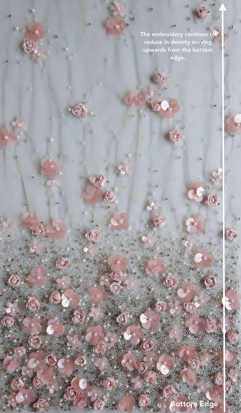 以下が含まれることがあります： 薄いグレーの生地にピンクの花の刺繍と白いビーズが施されたクローズアップ。刺繍は下部が濃く、上部に行くにつれて薄くなっている。テキスト「The embroidery continue to reduce in density moving upwards from the bottom edge.」と「Bottom Edge」が表示されている。