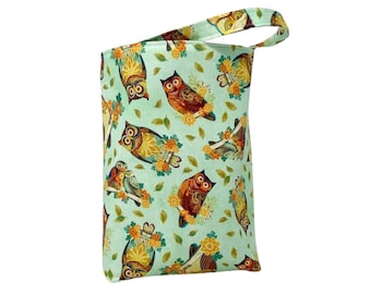 Pode incluir: Uma bolsa de carro de tecido verde com uma alça marrom. A bolsa tem um padrão repetitivo de corujas coloridas em um fundo verde claro. O texto "Handcrafted Car Bag" está escrito abaixo da bolsa.
