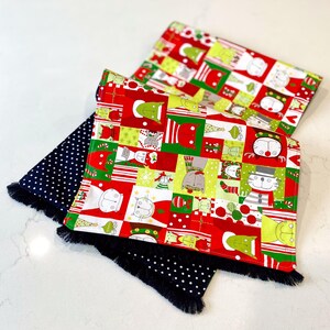 Könnte beinhalten: Zwei Weihnachtstischläufer mit einem schwarz-weißen Tupfenmuster und einem rot-grün-weißen Muster mit Katzen, die Weihnachtsmützen und andere festliche Kleidung tragen.