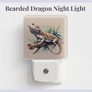 May include: A beige night light with a bearded dragon on a branch with green leaves. The dragon is brown, tan, and gray with a light blue beard. The night light plugs into an outlet.