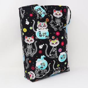 May include: Black tote bag with a repeating pattern of sugar skull cats in fish bowls. The cats are white with black skeletal features and pink, blue, and yellow accents. The fish bowls are blue with orange and white fish.