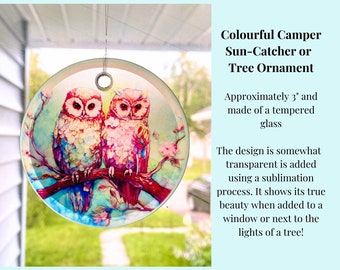 Pode incluir: Um apanhador de sol ou ornamento de árvore de vidro redondo com duas corujas coloridas empoleiradas em um galho com flores rosa. O design tem aproximadamente 7,6 cm de diâmetro e é feito de vidro temperado.