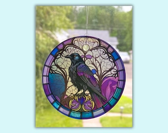 Pode incluir: Um apanhador de sol de vitral com um corvo preto com detalhes em roxo, azul e amarelo. O corvo está empoleirado em um galho com intrincados desenhos florais.