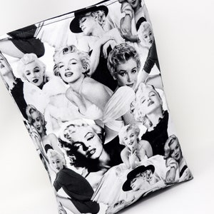 Puede incluir: Bolsa de tela negra y blanca con un collage de im&aacute;genes de Marilyn Monroe. La bolsa est&aacute; hecha de tela y tiene una forma rectangular.