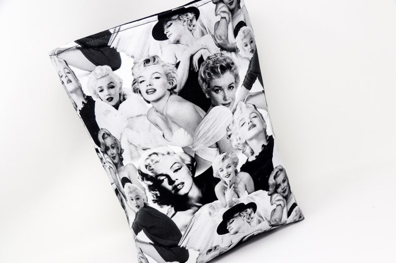 Puede incluir: Bolsa de tela negra y blanca con un collage de im&aacute;genes de Marilyn Monroe. La bolsa est&aacute; hecha de tela y tiene una forma rectangular.