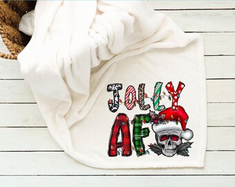 Pode incluir: Cobertor de lã branca com um design de Natal que apresenta as palavras "Jolly AF" em letras coloridas com luzes e uma caveira usando um chapéu de Papai Noel.