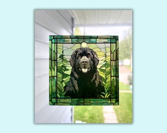 May include: A stained glass window hanging ornament featuring a black Newfoundland dog with green and brown foliage in the background.