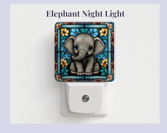 Pode incluir: Uma luz noturna com um design de vitral de um elefante bebê com flores azuis, verdes e amarelas. A luz noturna é branca e tem um design de tomada.