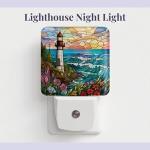 Peut inclure: Veilleuse décorative avec une image de style vitrail d'un phare sur une côte rocheuse, des vagues océaniques et des fleurs. La veilleuse est blanche et possède une seule lumière.