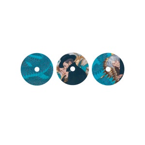 May include: Three round, blue and gold patterned coasters with images of people in hats. The coasters have a hole in the centre.