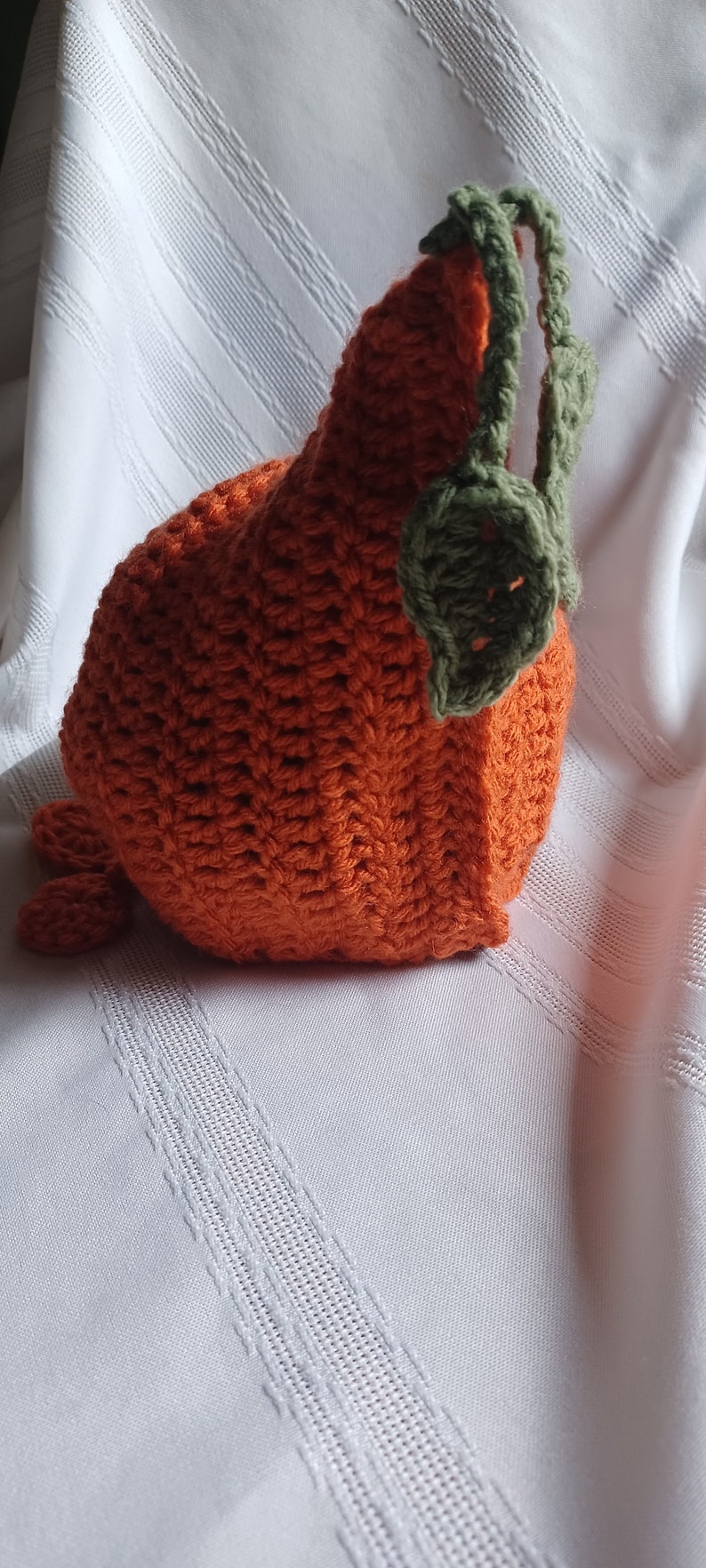 May include: Handmade orange crochet pumpkin with green leaves and stem. The pumpkin is made with a textured stitch and has a rounded shape. A charming fall decoration for the home.