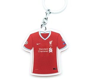 Könnte beinhalten: Ein roter Liverpool FC Fußballtrikot-Schlüsselanhänger mit dem Teamlogo und den Sponsoren, Standard Chartered, auf der Vorderseite. Der Schlüsselanhänger hat einen silbernen Metallring.