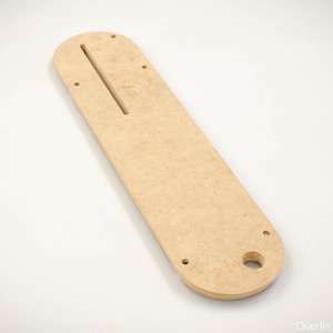 May include: A light brown wooden template with a long slot cut out and several holes drilled into it. The template is designed for woodworking projects.