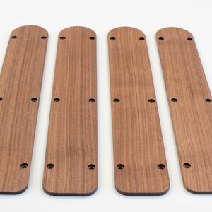 Puede incluir: Cuatro tiras de madera con bordes redondeados y varios agujeros perforados a lo largo de su longitud. Las tiras son de color marr&oacute;n claro y tienen un patr&oacute;n de veta de madera.