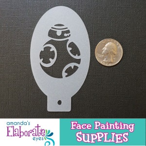 May include: A light gray plastic face painting stencil in an oval shape, featuring a BB-8 droid design. A U.S. quarter coin is next to the stencil for size comparison. The bottom of the image has a logo and text that reads "Face Painting SUPPLIES".