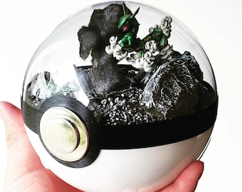 Könnte beinhalten: Eine klare Glaskuppel mit einer schwarz-weißen Pokeball-Basis. Im Inneren der Kuppel steht eine grün-schwarze Pokemon-Figur auf einem Bett aus schwarzen Steinen und Moos.