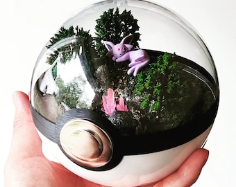 May include: A glass terrarium shaped like a Pokeball with a purple Pokemon figurine, green moss, and pink crystals inside.