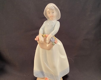 Estatueta vintage de porcelana representando uma menina com uma cesta de flores.