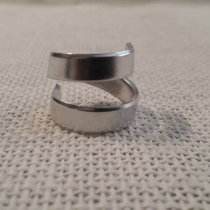 May include: A silver ring with a double band design. The ring is made of metal and has a smooth finish.