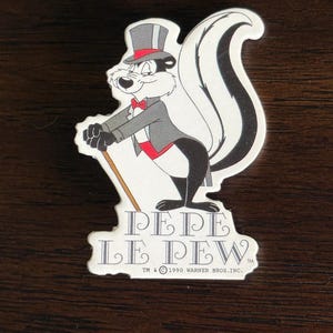 May include: A sticker featuring Pepe Le Pew, a cartoon skunk character. The skunk is depicted in a tuxedo and top hat, holding a cane. The sticker has the text "PEPE LE PEW" and the Warner Bros. Inc. copyright.