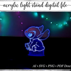 May include: A blue acrylic light stand featuring a cartoon character design. The stand is illuminated with a bright blue light, set against a dark background with colorful string lights. Text at the top reads "acrylic light stand digital file".