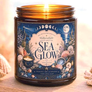 May include: A lit candle in an amber glass jar with a label featuring a blue coastal illustration, a lighthouse, moon phases, and seashells. The text reads Sea Witch Botanicals, Sea Glow, Coconut Apricot Wax, Unscented, and Fragrance-Free Illumination.