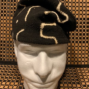 May include: A black and white patterned knit hat with a geometric design. The hat is folded over and has a soft, textured feel.