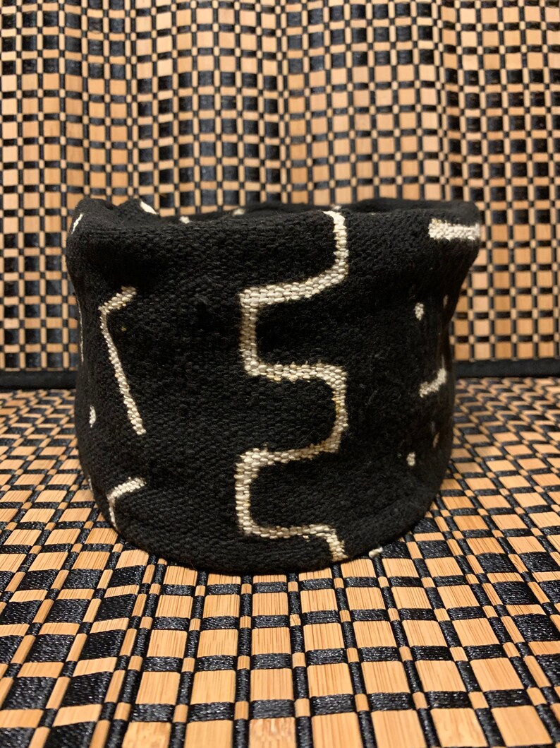 May include: Black and white woven basket with a geometric pattern. The basket is made of a soft, textured fabric.