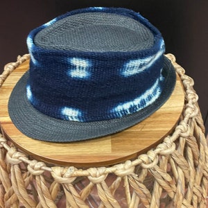 May include: A blue and white patterned hat with a wide brim. The hat is made of a woven material and has a dark blue band around the crown.