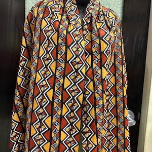 May include: A long black, red, white, and yellow scarf with a geometric pattern.