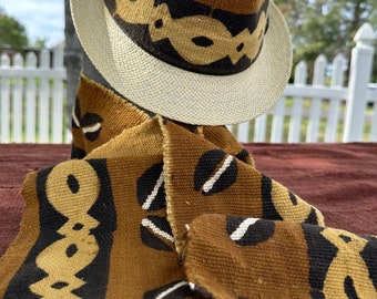 May include: A brown and tan woven hat with a white band and a brown and tan woven scarf with a white design.