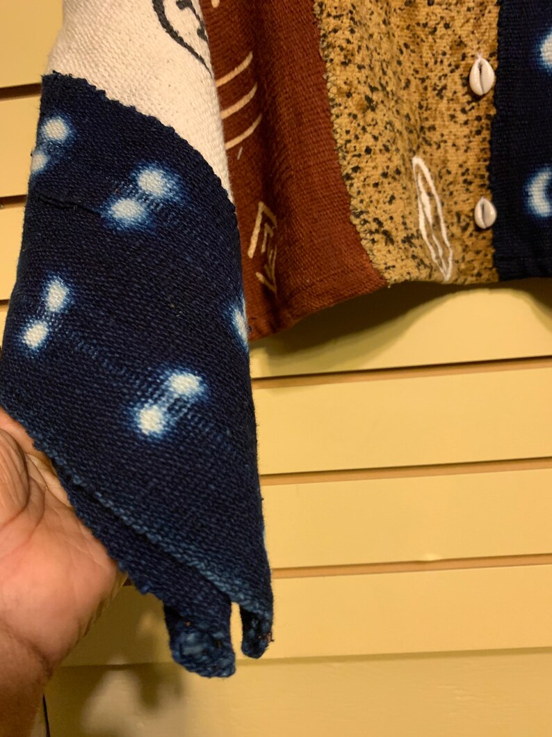 May include: A blue and white fabric with a pattern of small white circles. The fabric is folded in a triangular shape and is held in a hand.