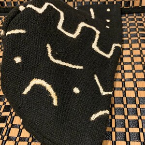 May include: Black fabric pouch with a white geometric pattern. The pouch is made of a soft, textured material.