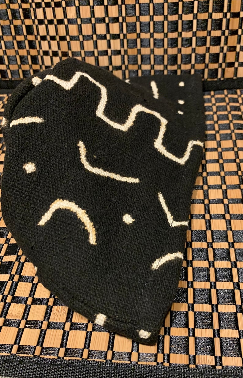 May include: Black fabric pouch with a white geometric pattern. The pouch is made of a soft, textured material.