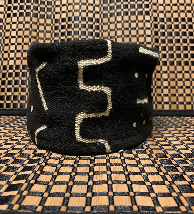 May include: Black and white woven storage basket with a geometric pattern. The basket is made of a thick, textured fabric.