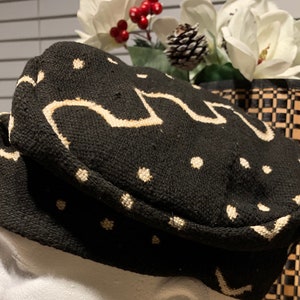 May include: A black and white patterned fabric hat with a rounded crown and a flat brim. The hat has a white geometric design and white dots.