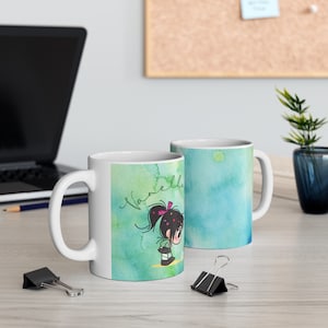 May include: Two white ceramic mugs with a watercolor background. One mug features a cartoon girl with a pink bow in her hair and the name "Vanella" written in cursive. The other mug has a blue and green watercolor background.