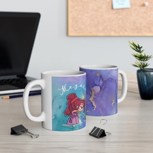 May include: Two white ceramic mugs with a blue and purple watercolour design. One mug features a cartoon illustration of a woman with red hair and the name "Mega" written in cursive. The other mug has a gold glitter design.