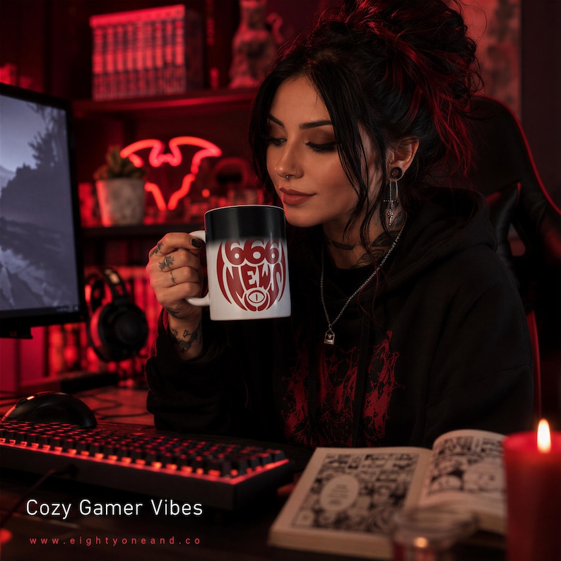 A woman with dark hair is sitting at a desk, holding a mug with a red and white design, and looking at a book. The background includes a computer monitor, keyboard, and a candle.