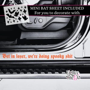 May include: A car door with a black interior and a silver door frame. The image includes a sheet of bat and star stickers, and text that reads "Get in loser, we're doing spooky shit."