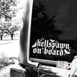 May include: Black and white image of a car window with a white decal that reads "hellspawn on board" in a gothic font. The decal includes star and bat illustrations. The Etsy shop name "Eighty One & Co" is also visible.