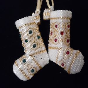 May include: Two white beaded Christmas stockings with gold and bead accents. One stocking has green beads and the other has red beads.