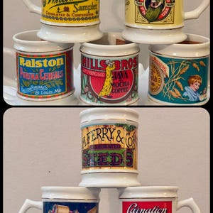 May include: A collection of vintage ceramic mugs with various brand labels. The mugs feature designs for salt, chocolates, coffee, cereal, seeds, milk, soap, and tobacco. Each mug has a handle and a decorative rim.