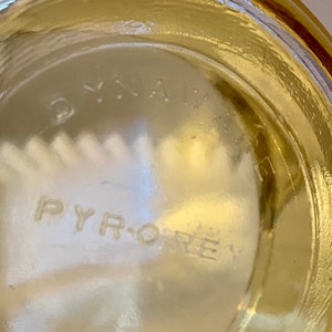 May include: Close-up of the bottom of a clear glass jar with the words "PYRO-REX" embossed on the bottom.