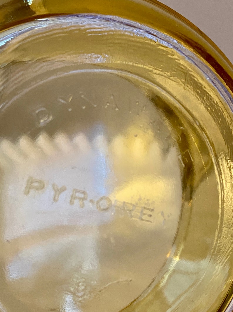May include: Close-up of the bottom of a clear glass jar with the words "PYRO-REX" embossed on the bottom.