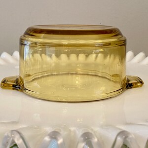 May include: A clear amber glass baking dish with two handles. The dish is round and has a slightly flared rim.