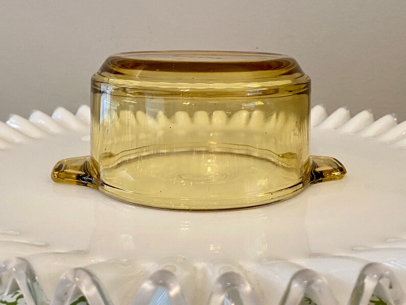 May include: A clear amber glass baking dish with two handles. The dish is round and has a slightly flared rim.